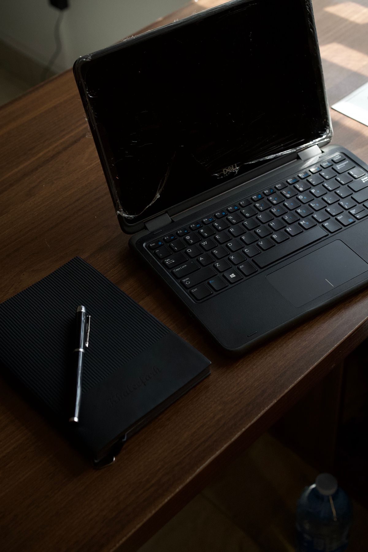Dark desk with laptop, notebook, and pen